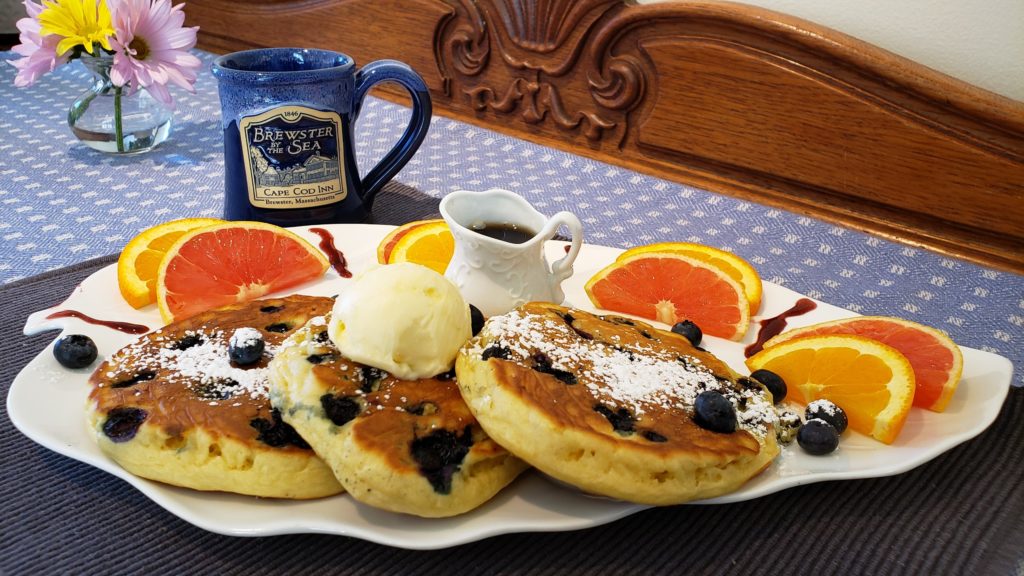 Blueberry Crumb Pancakes on a plate with orange slices and maple syrup