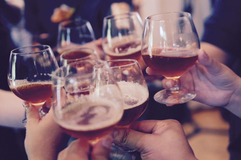 Hands cheersing small glasses of beer