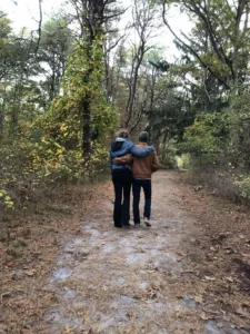 Two individuals strolling along a forest trail.